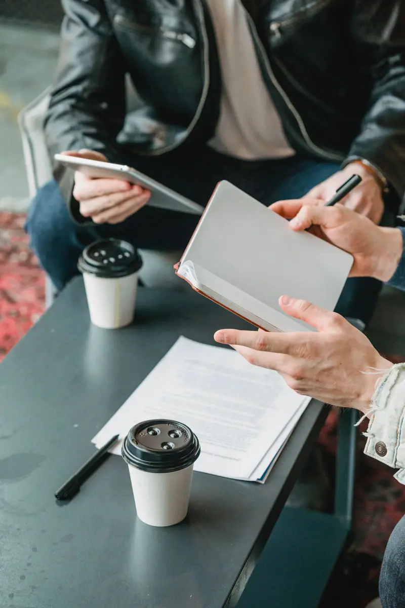Colleagues planning work with a tablet and notebook.